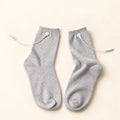 TENS electrode socks with white cables on warm ivory background
